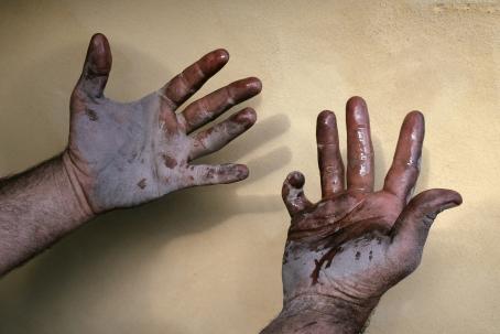 Ihmisen kädet kämmenpuoli ylöspäin. Kädet ovat likaiset ja märät. 