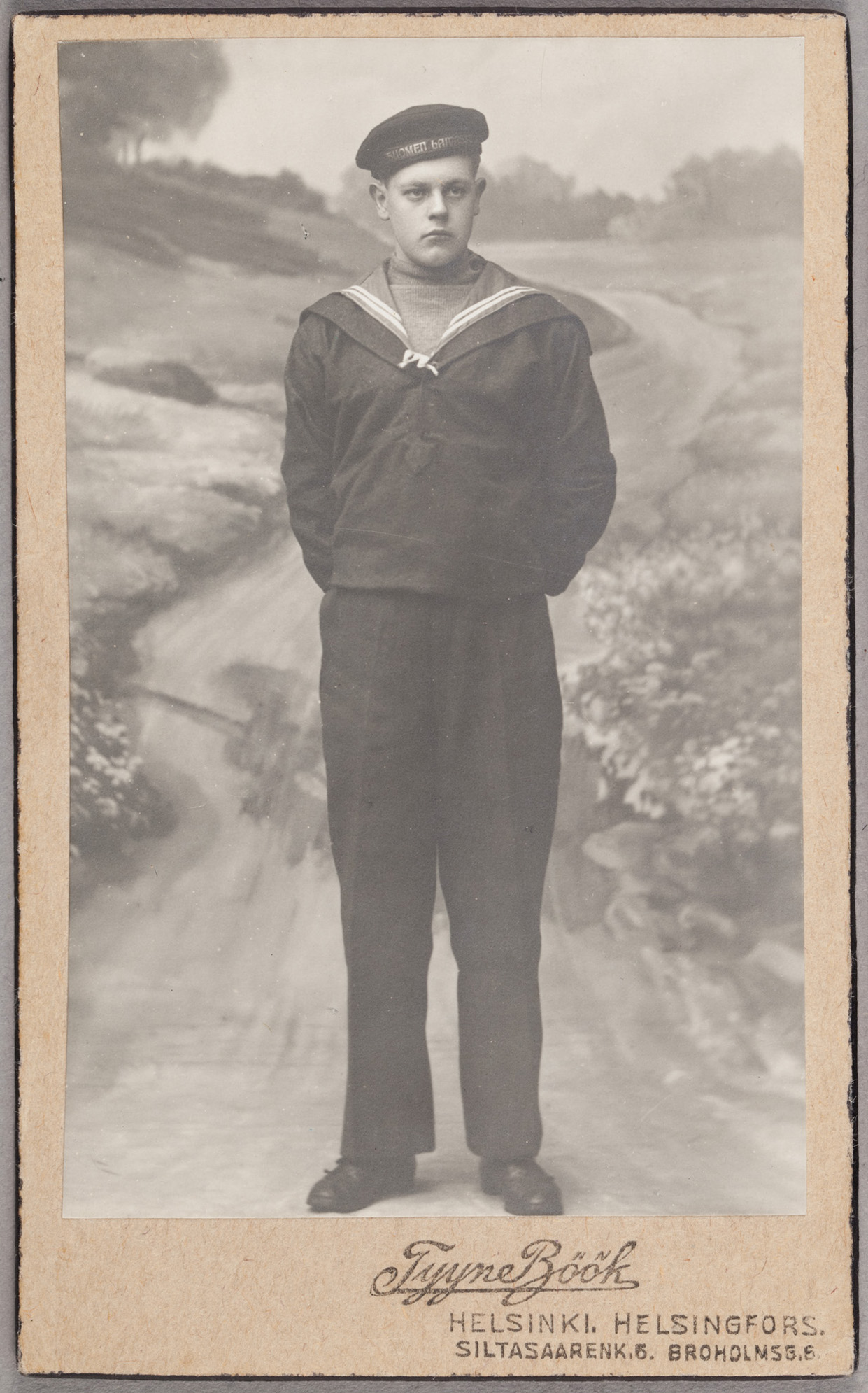 Merimies pohtii olevaista maantiellä, vaiko sittenkin joessa seisten? Lieköhän kyseessä ollut kuvaamon ainoa veteen viittaava taustakangas? Kuva: Tyyne Böök, noin 1915, visiittikortti. Suomen valokuvataiteen museo. D2003:108/16