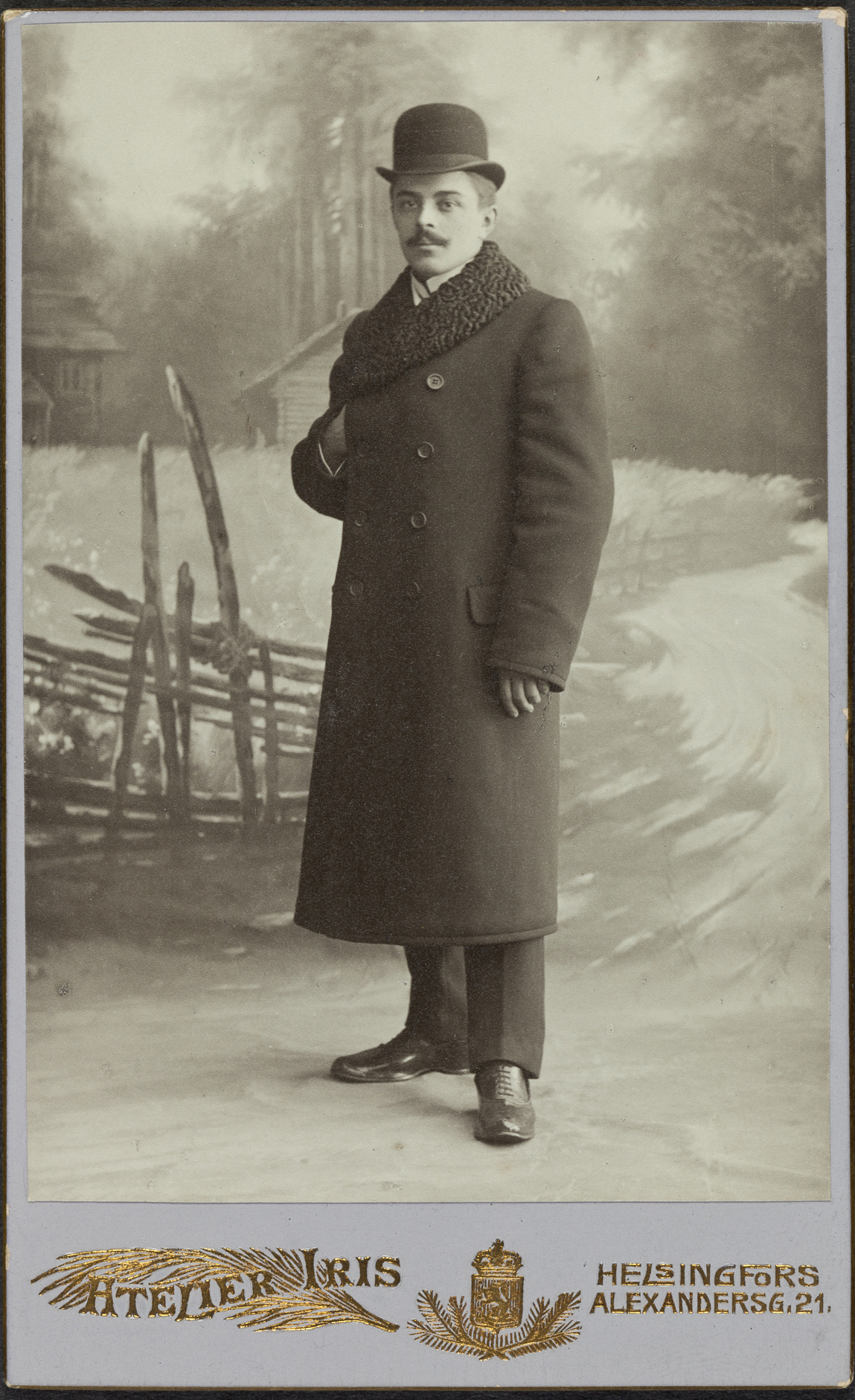 Tämä helsinkiläisherra näyttää knallissa ja hienossa krimikauluksisessa palttoossaan hieman eksyneeltä viljapellon edessä. Kuva: Atelier Iris, noin 1910, visiittikortti. Suomen valokuvataiteen museo. D2004:108/6