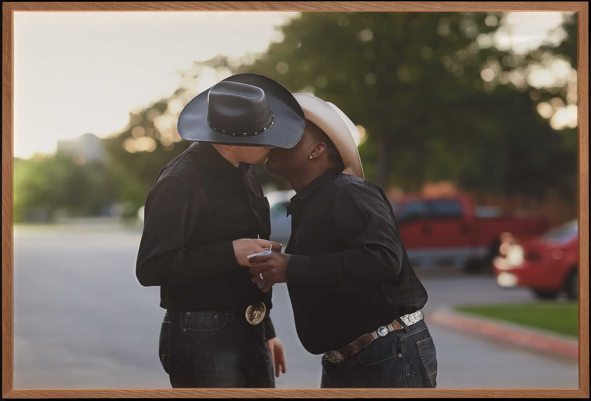 Kaksi cowboytä suutelee International Gay Rodeo -tapahtuman finaaleissa Fort Worthissa, Yhdysvalloissa. Stetsonit peittävät puolikuvassa kuvattujen henkilöiden kasvonsa. Heillä on käsissään kertakäyttöiset kahvimukit.