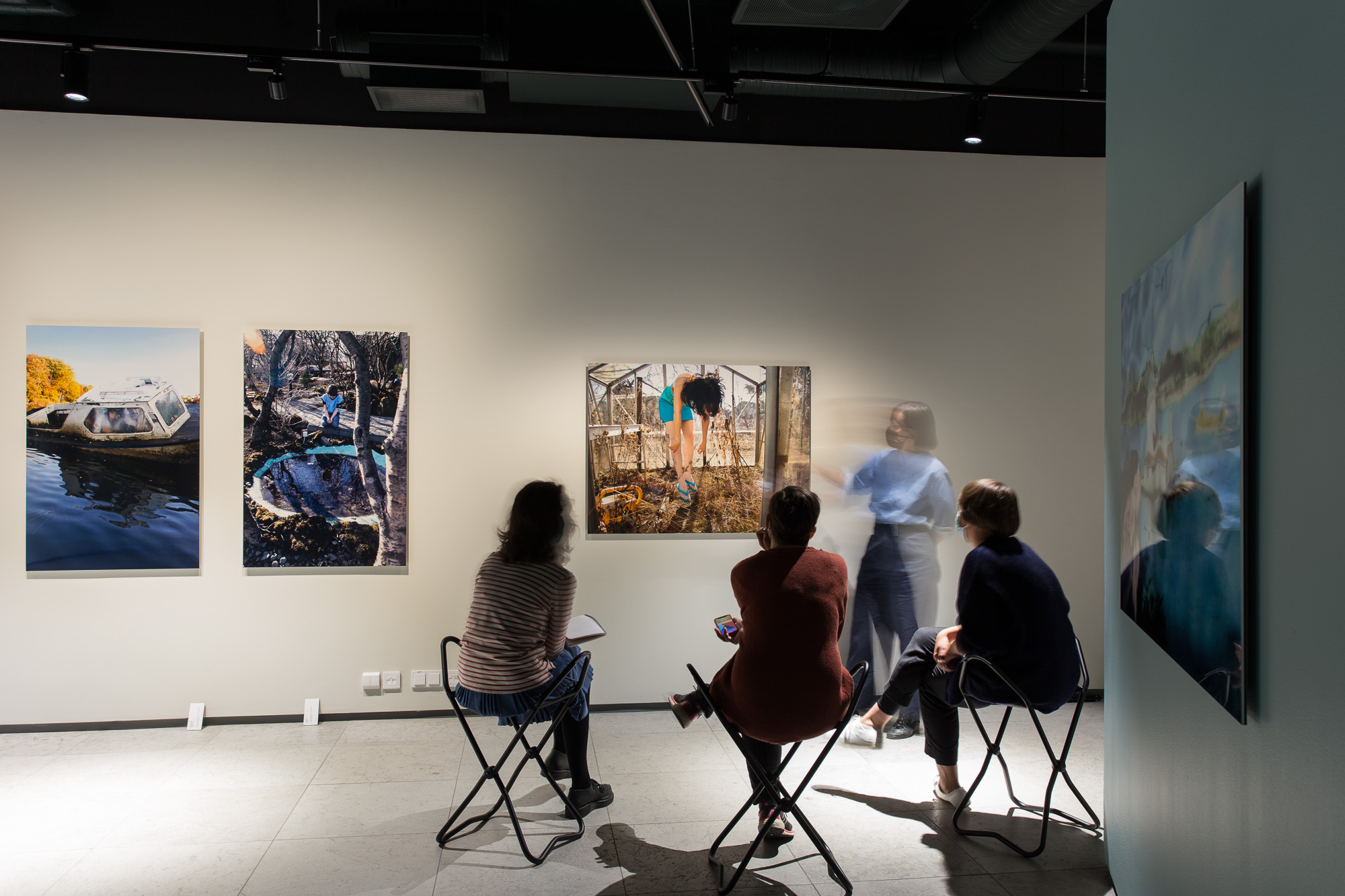 People sitting on chairs in the gallery space.