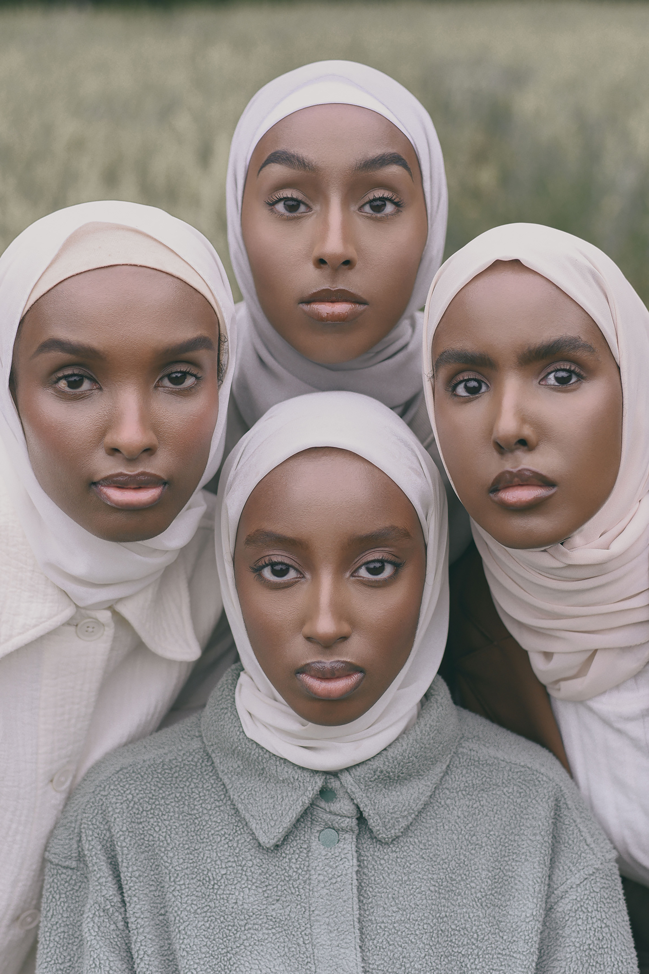 Ryhmäkuva, muotikuva. Neljä tummaihoista nuorta naista poseeraa symmetrisessä muodostelmassa, kasvot ja katse kohdistettuina kameraan. 