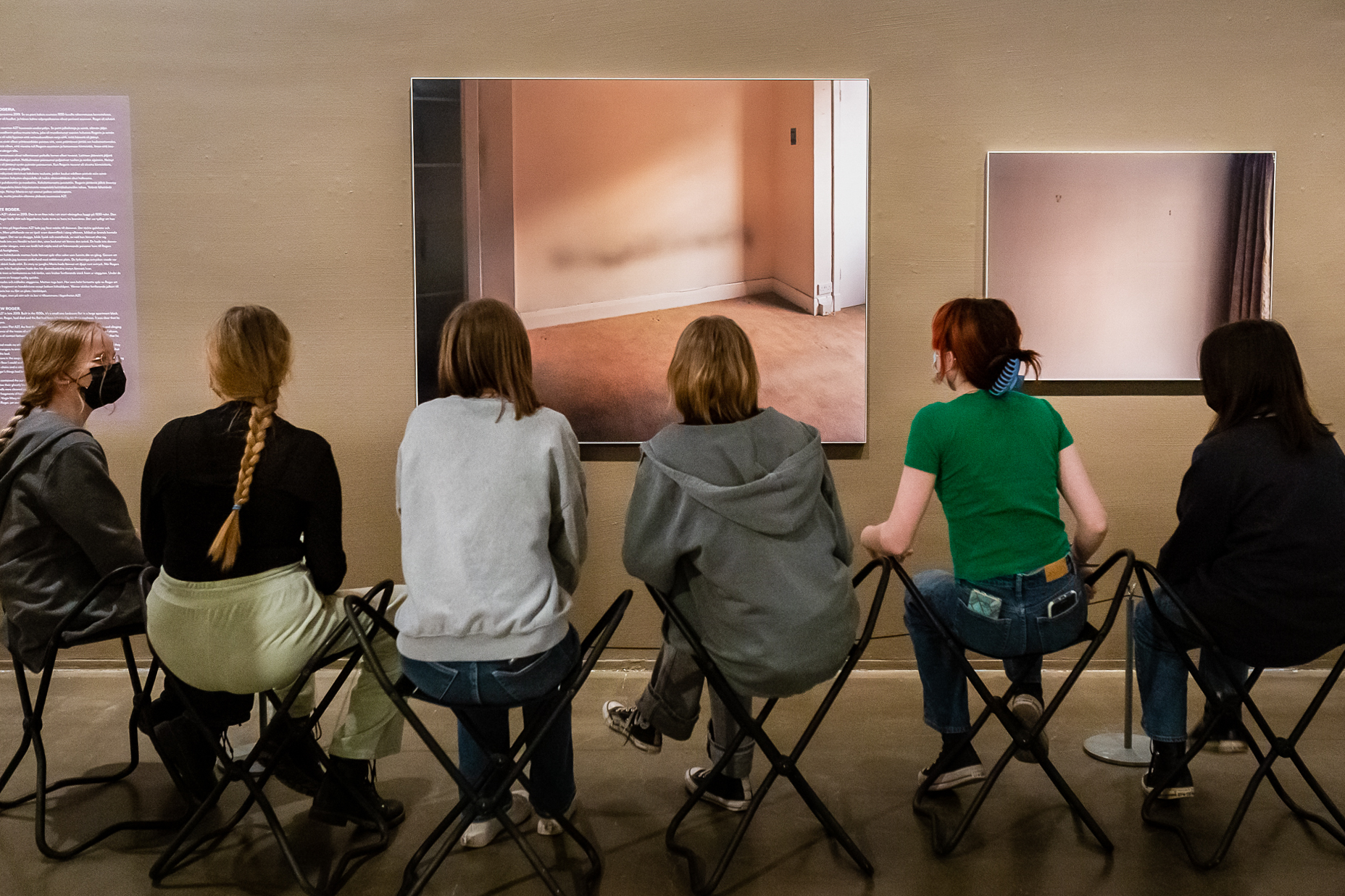 People sitting on chairs in the gallery space.