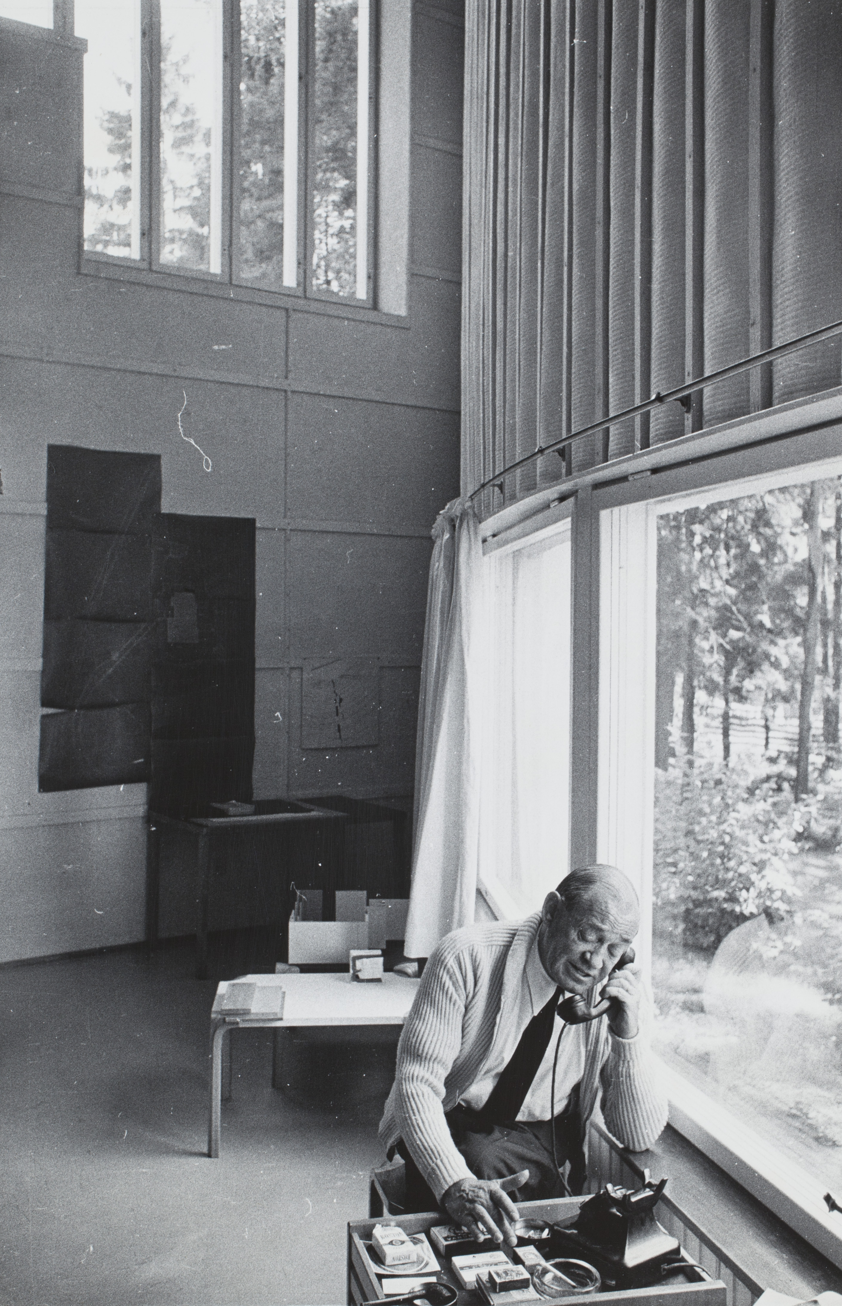 Arkkitehti, professori Alvar Aalto puhuu puhelimessa työhuoneessaan. K-G Roos, sarjasta Ihmisten Helsinki, Helsinki, 1960. Suomen valokuvataiteen museo.