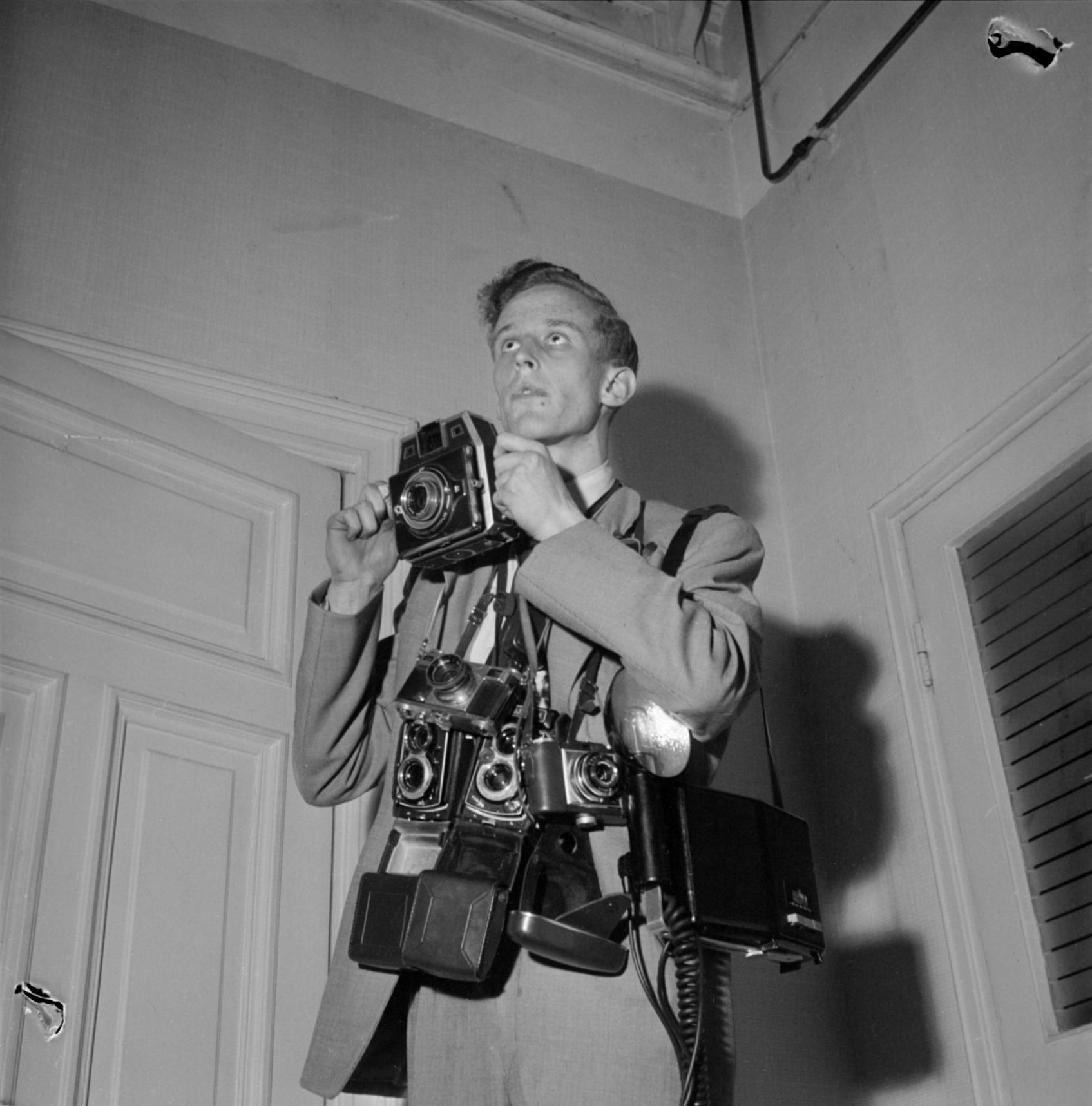 Uuden Suomen valokuvaaja Seppo Heikinheimo poseeraa kameroineen 1957 Helsingissä. Uuden Suomen kokoelmat. Suomen valokuvataiteen museo.