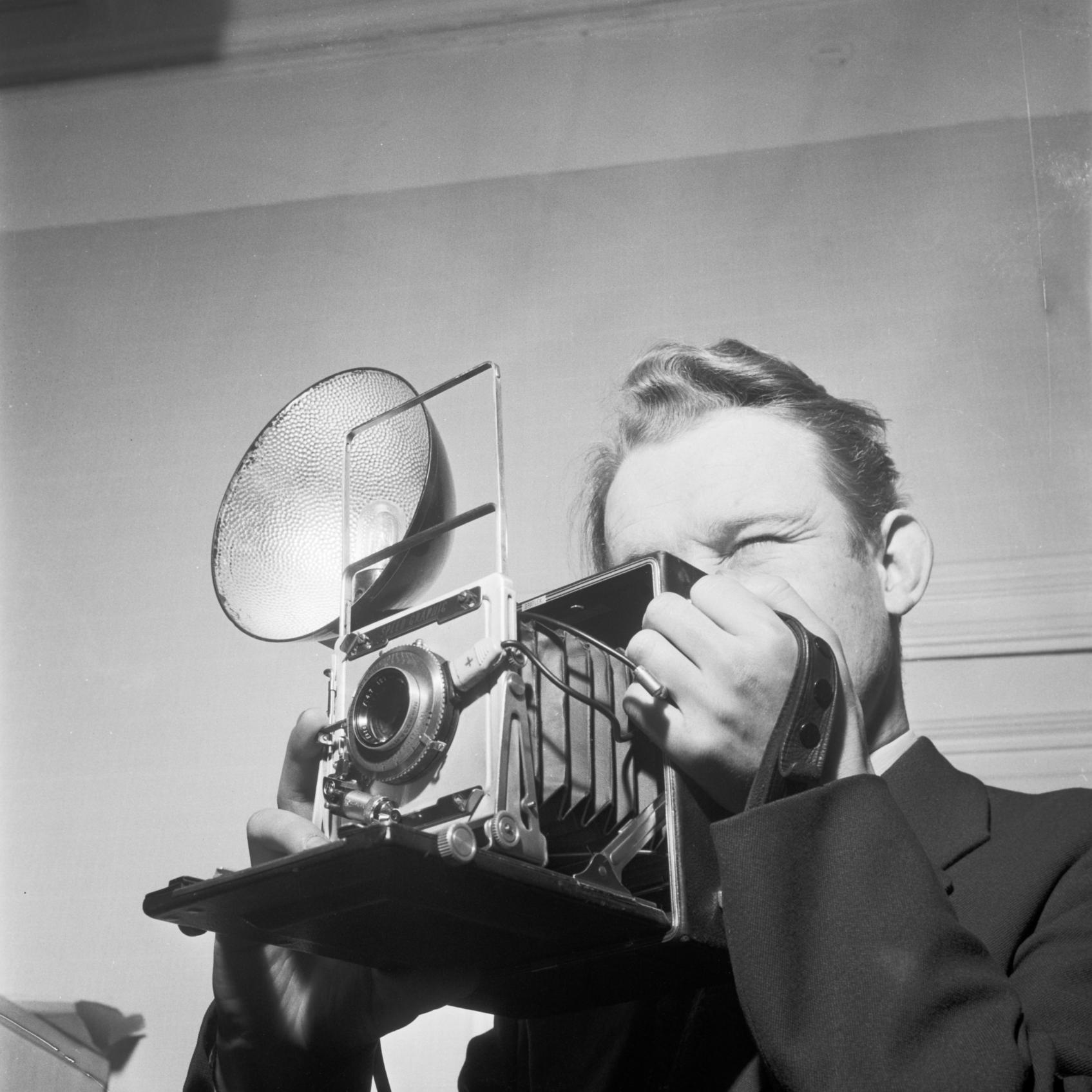 Lehtikuvaaja työssään 1955, kamerana Graflex Speed Graphic. Uuden Suomen kokoelma. Suomen valokuvataiteen museo.