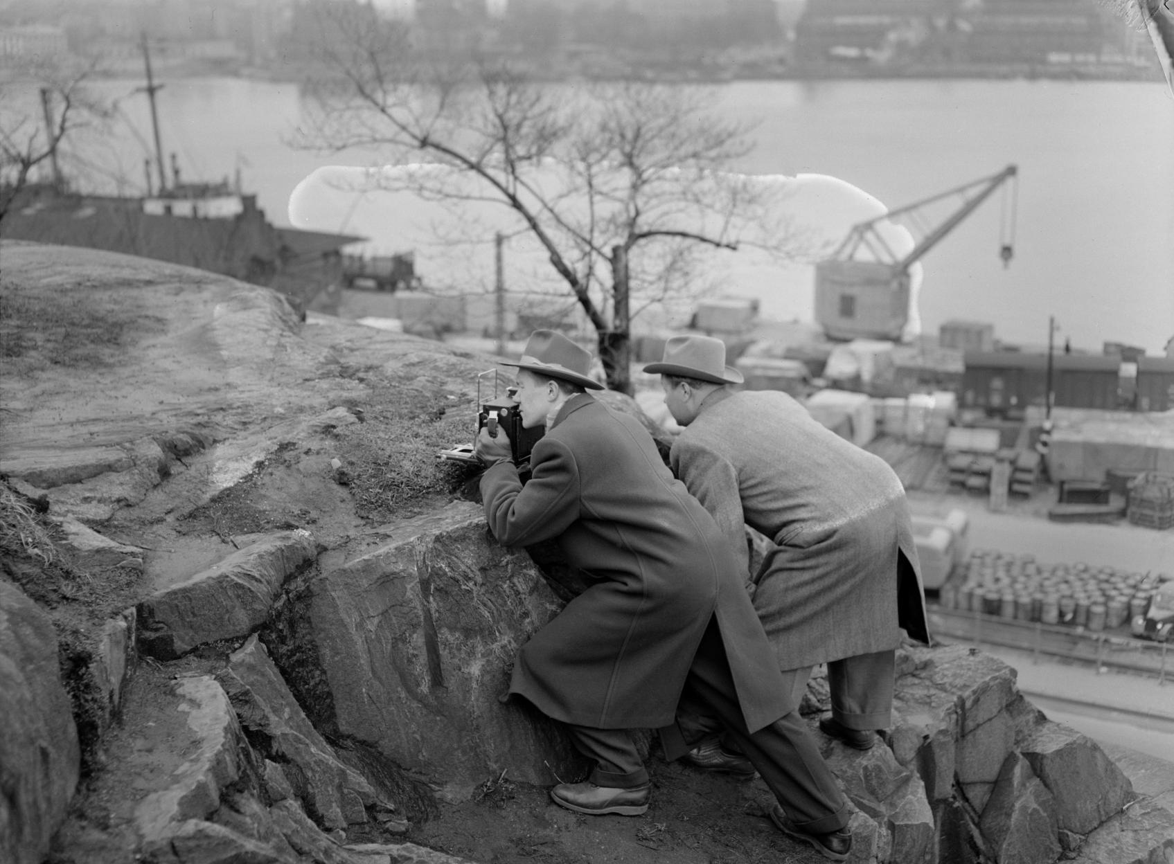 Uuden Suomen valokuvaaja ja toimittaja keikkuvat työssään kalliokielekkeellä. Valokuvaaja tuntematon. Uuden Suomen kokoelma, Suomen valokuvataiteen museo, 1955.