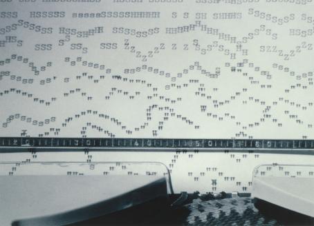 Kirjoituskoneessa oleva paperi, johon on kirjoitettu aaltoileviin jonoihin kirjaimia ja välimerkkejä.