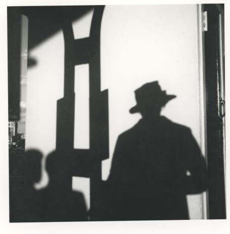 Vivian Maier, Chicago, ei päiväystä. © Estate of Vivian Maier, Courtesy of Maloof Collection and Howard Greenberg Gallery, NY. Mustavalkoisessa kuvassa vaaleaan seinään heijastuu hattupäisen ihmisen varjo. Vieressä näkyy jonkin rakennelman varjo sekä kahden lapsen varjo.