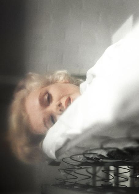 Marilyn Monroe makaa sängyllä. Kuva on otettu alhaalta päin, ja siinä näkyy sängyn jouset ja patja, jonka yläpuolella on Monroen kasvot. Kuva on hieman sumuinen.