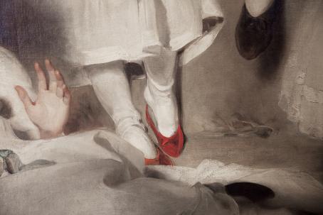 Jalat joissa on valkoiset sukkahousut ja punaiset kengät. Niiden yläpuolella näkyy osa valkoisesta mekosta. Etualalla olevasta valkoisesta kankaasta nousee käsi.