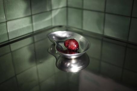 Kliinisen näköisellä metallitasolla on metallinen astia, jossa on punainen möykky. 