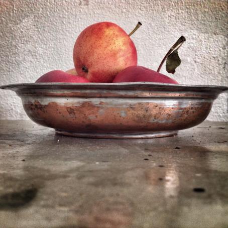 Pöydän tasosta kuvattu kulho, jossa on omenoita. 