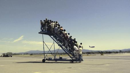 Lentokentällä olevat siirrettävät portaat ovat täynnä ihmisiä, mutta portaiden vieressä ei ole lentokonetta.