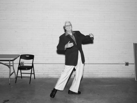 Mustavalkoisessa kuvassa vanha mies on tanssivassa asennossa, hän on laittanut kätensä näkymättömän ihmisen ympärille. 