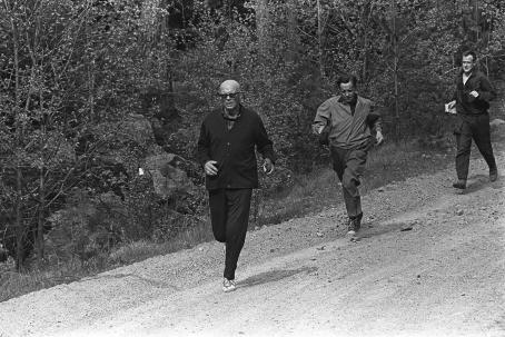 Kekkonen juoksee maantiellä, Kaarlo Leinonen seuraa perässä. Kalle Kultala, Upinniemi, 1964. Suomen valokuvataiteen museo.