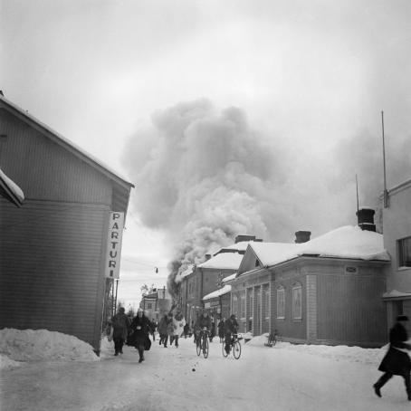 Ihmiset pakenevat turvaan Neuvostoliiton lentopommituksilta. Palopommi on sytyttänyt rakennuksen Kouvolan keskustassa. 30.11.1939