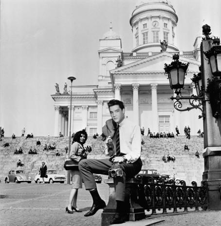 Mustavalkoisessa kuvassa Elvis istuu Senaatintorilla olevan patsaan ympärillä olevalla aidalla. Hänellä on puku päällä ja hän pitää puvuntakkia olallaan. Toisessa kädessä hänellä on filmikamera. 