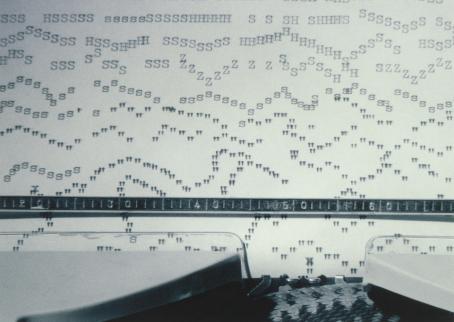 Kirjoituskoneessa oleva paperi, johon on kirjoitettu aaltoileviin jonoihin kirjaimia ja välimerkkejä.