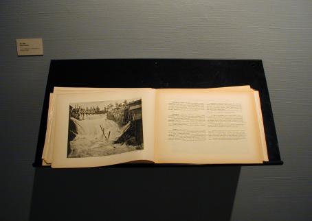 Näyttelyssä esillä oleva kirja, jossa näkyy Inhan valokuva koskesta sekä tekstiä, josta ei saa selvää.