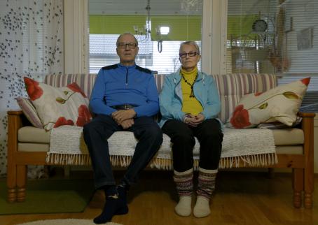 Vanhempi mies ja nainen istuvat sohvalla vierekkäin.