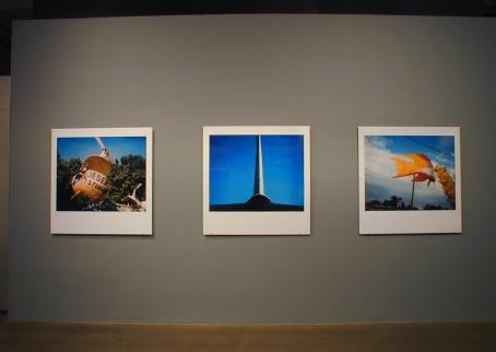 Kolme polaroid-kuvaa vierekkäin näyttelytilassa.